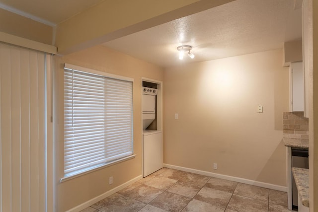 interior space with a fireplace, a textured ceiling, and stacked washer and dryer