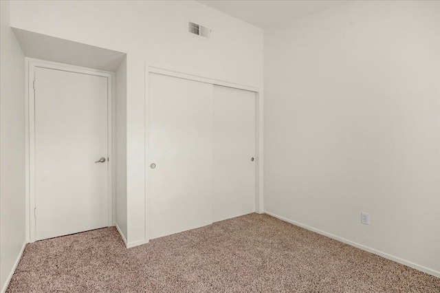 unfurnished bedroom featuring light colored carpet and a closet