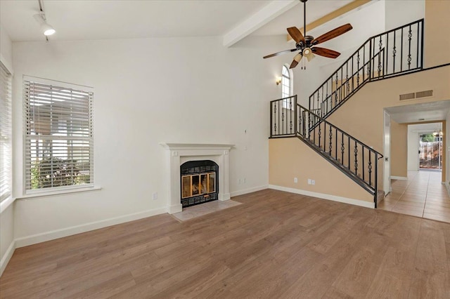 unfurnished living room featuring ceiling fan, light hardwood / wood-style flooring, and lofted ceiling with beams