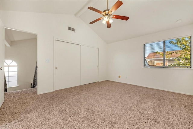 unfurnished bedroom featuring carpet flooring, ceiling fan, a closet, and lofted ceiling with beams