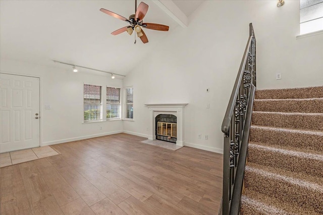 unfurnished living room with hardwood / wood-style floors, high vaulted ceiling, rail lighting, ceiling fan, and beam ceiling