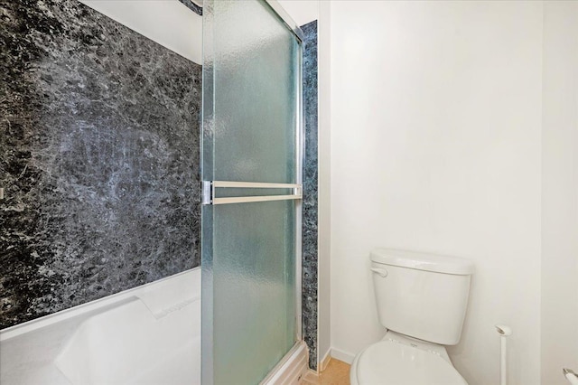 bathroom featuring a shower with shower door and toilet