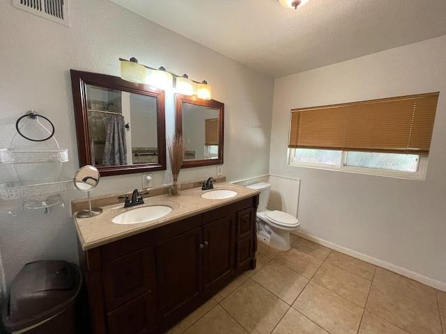 bathroom featuring tile patterned floors, walk in shower, vanity, and toilet