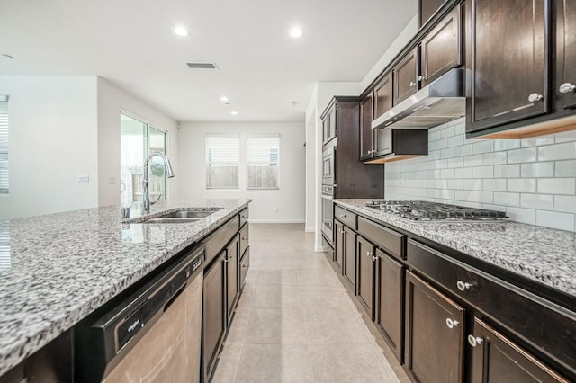 kitchen featuring backsplash, sink, light stone countertops, dark brown cabinetry, and stainless steel appliances