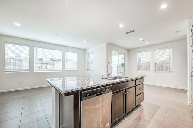 kitchen featuring light stone countertops, dishwasher, sink, a kitchen island with sink, and dark brown cabinets