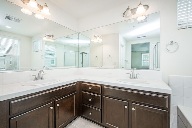 bathroom with tile patterned flooring, vanity, and walk in shower