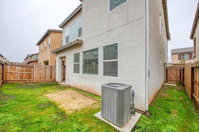 rear view of property featuring central air condition unit and a lawn