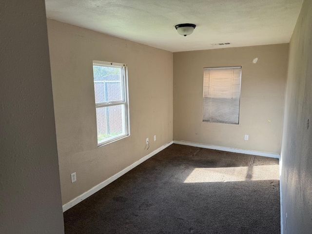 unfurnished room with dark colored carpet