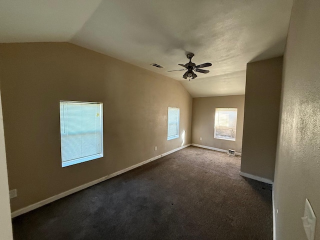 spare room featuring vaulted ceiling, dark carpet, and ceiling fan