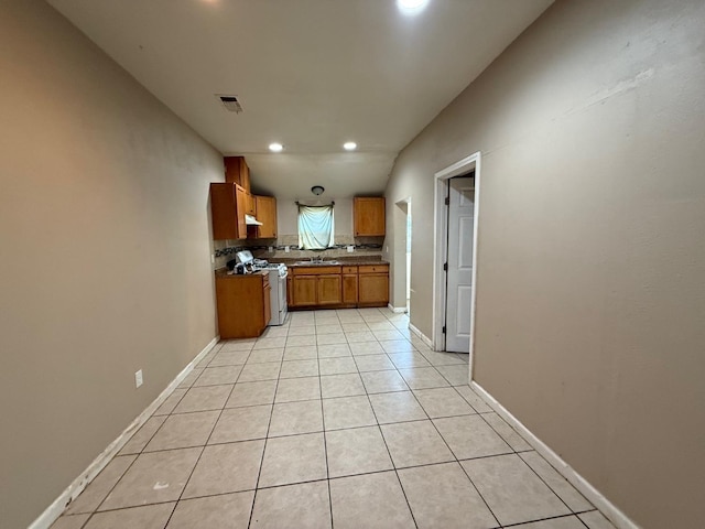 kitchen with light tile patterned floors, sink, white gas range oven, and backsplash