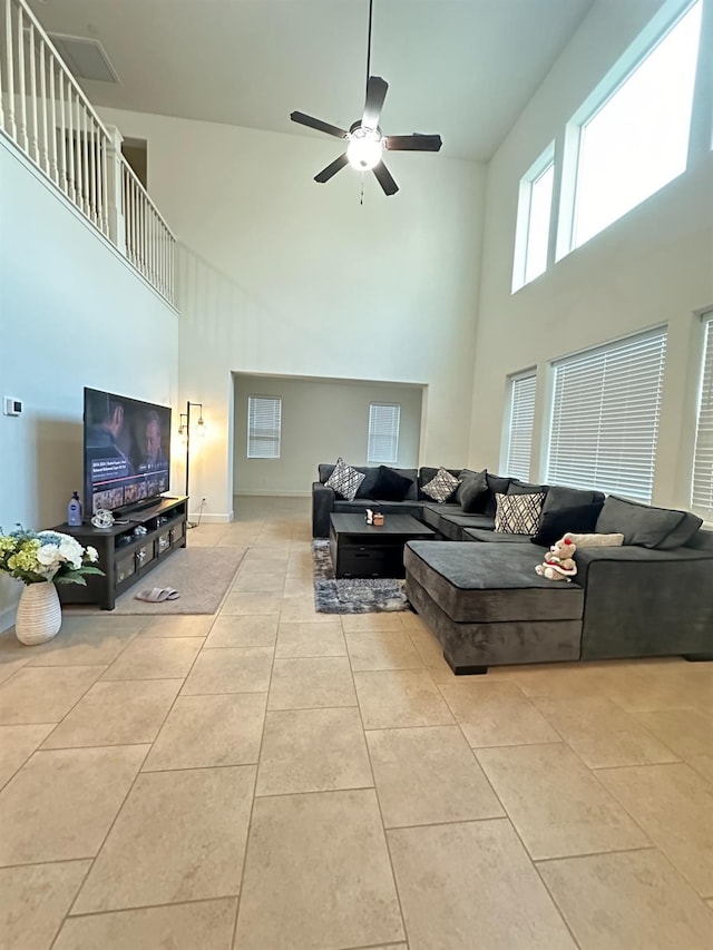 living room with ceiling fan, a towering ceiling, and light tile patterned floors