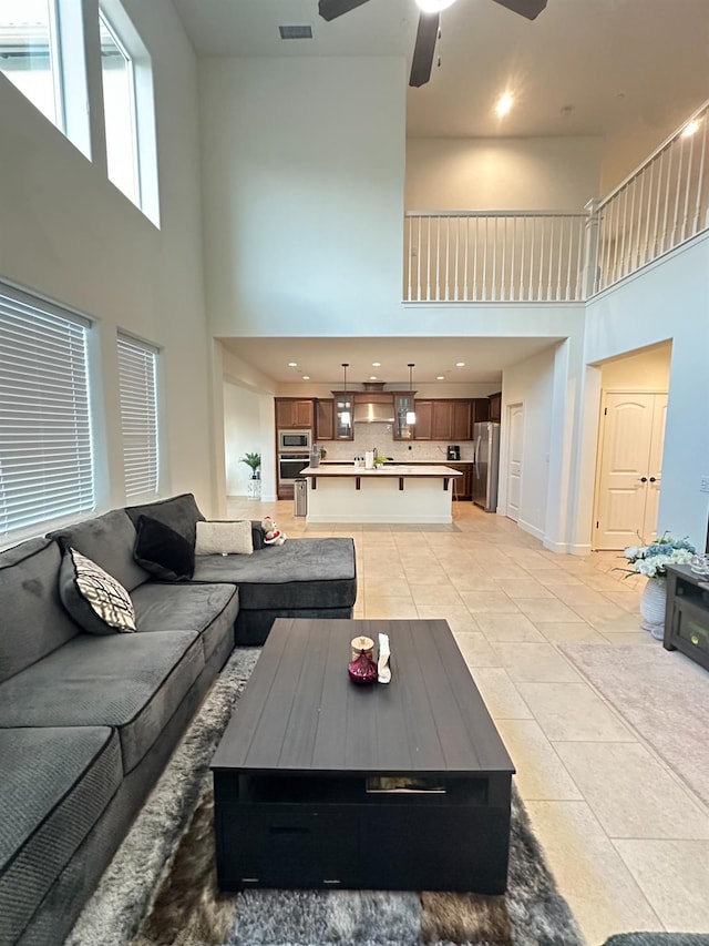 living room featuring ceiling fan, a towering ceiling, and light tile patterned flooring