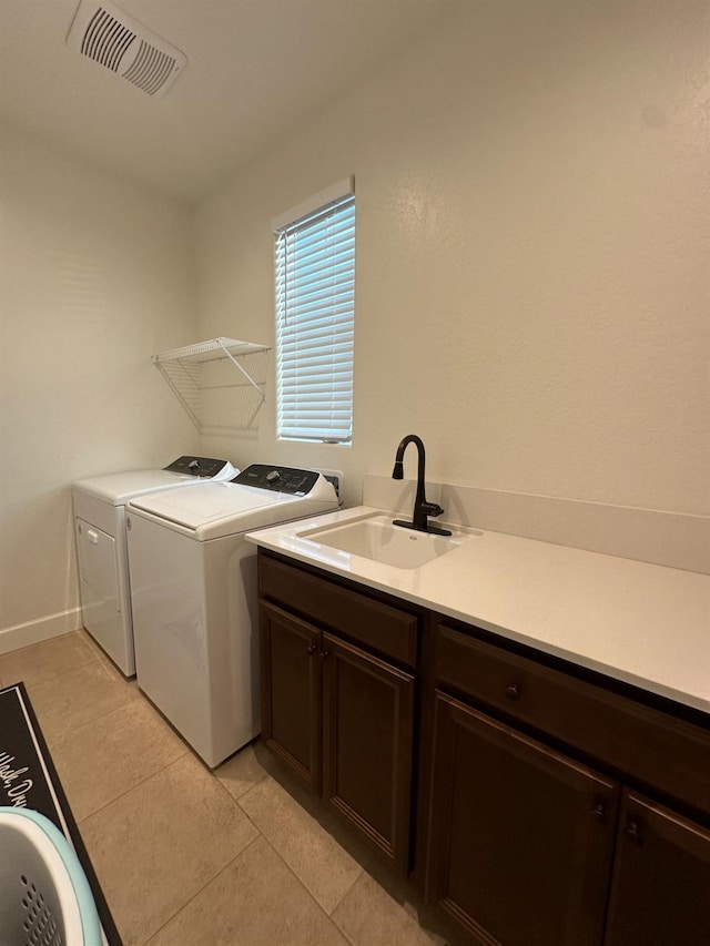 clothes washing area with washing machine and clothes dryer, sink, light tile patterned flooring, and cabinets