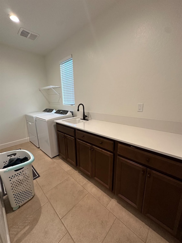 laundry area with cabinets, washing machine and dryer, light tile patterned floors, and sink