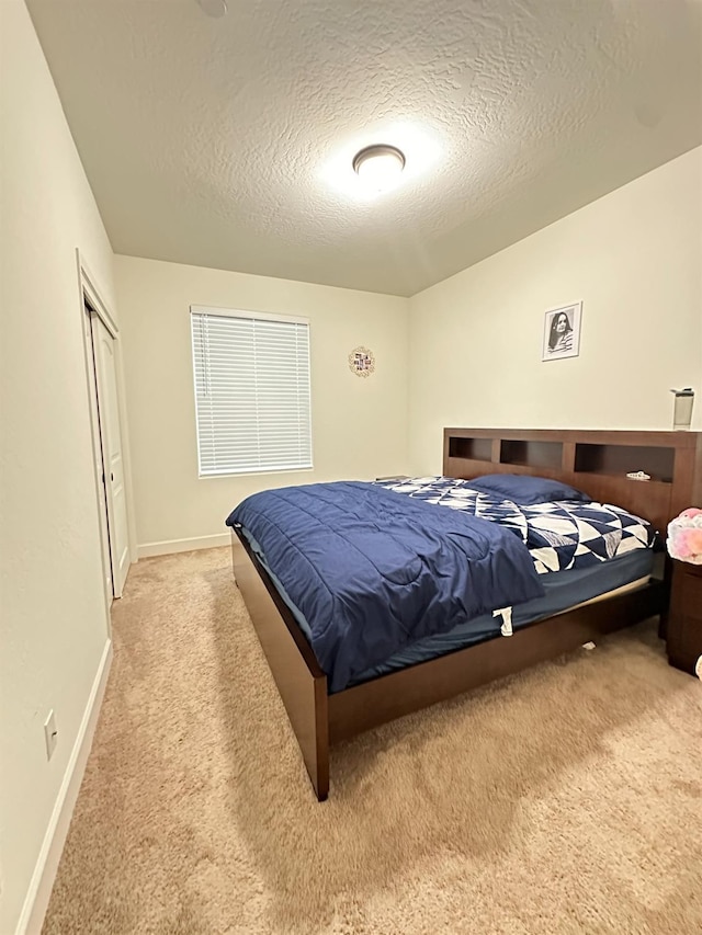 bedroom with light colored carpet and a textured ceiling