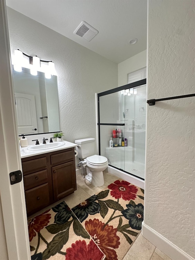 bathroom featuring toilet, vanity, tile patterned floors, and walk in shower