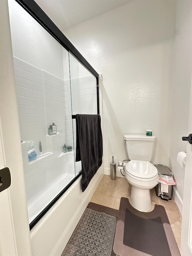 bathroom with tile patterned flooring, toilet, and shower / bath combination with glass door