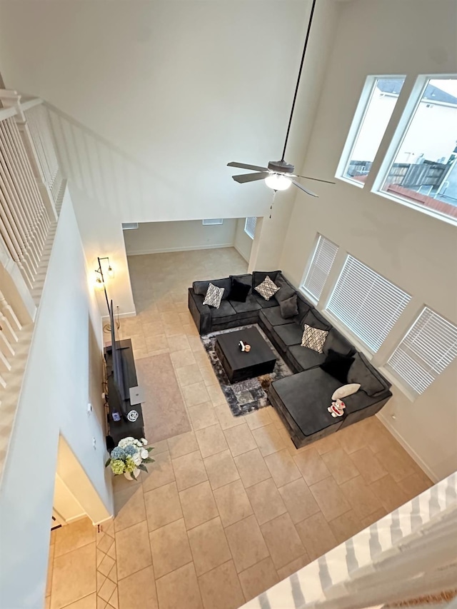 living room featuring ceiling fan, light tile patterned flooring, and a towering ceiling