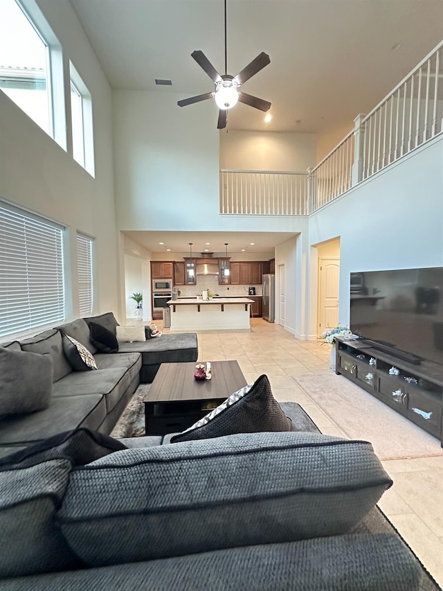 living room featuring ceiling fan, a towering ceiling, and light tile patterned floors