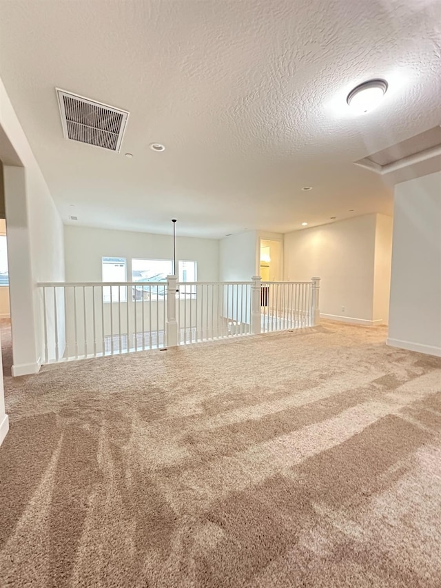 carpeted spare room with a textured ceiling