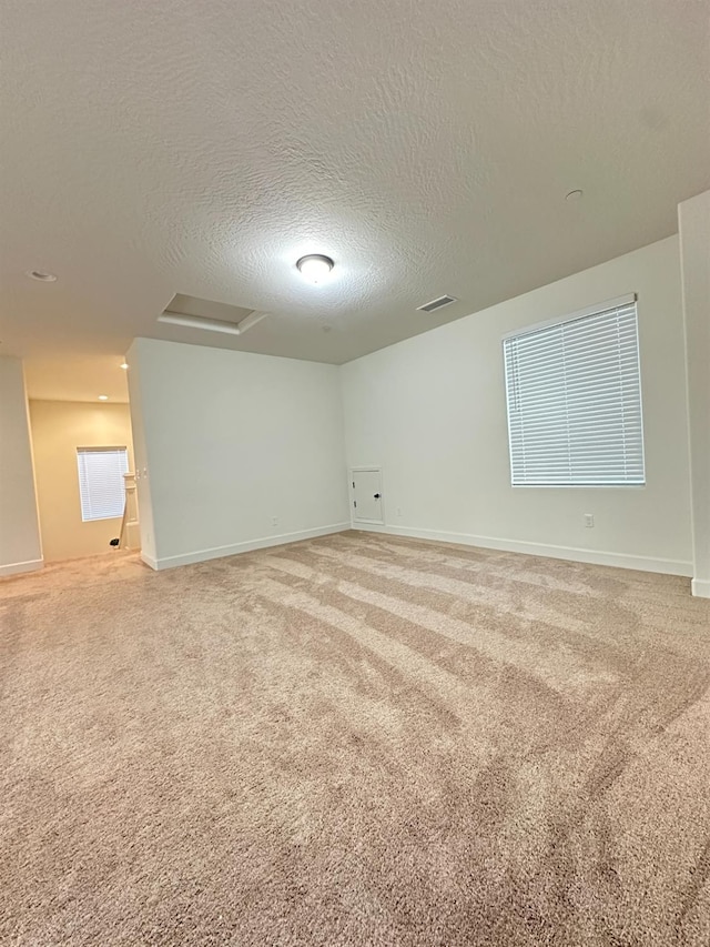 carpeted empty room featuring a textured ceiling