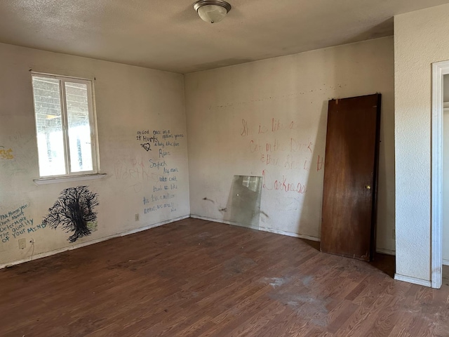 spare room featuring dark wood-type flooring and a textured ceiling