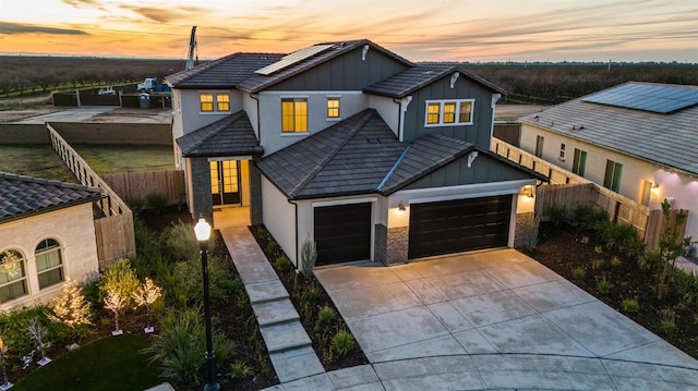 946 Talus Way S, Madera, CA 93636 - view of front of home with board and batten siding, an attached garage, roof mounted solar panels, driveway, and a tiled roof