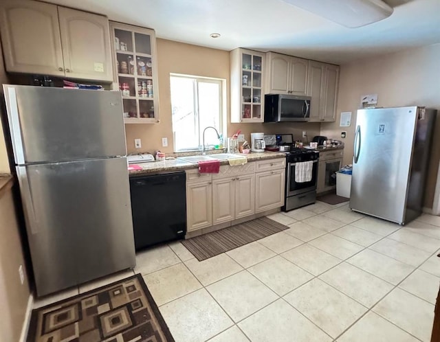 kitchen featuring light tile patterned floors, stainless steel appliances, light stone counters, and sink