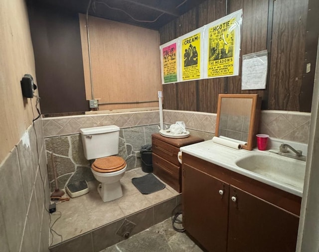 bathroom with vanity, toilet, and tile walls