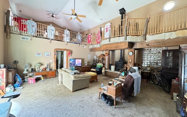 carpeted living room featuring a wood stove and high vaulted ceiling