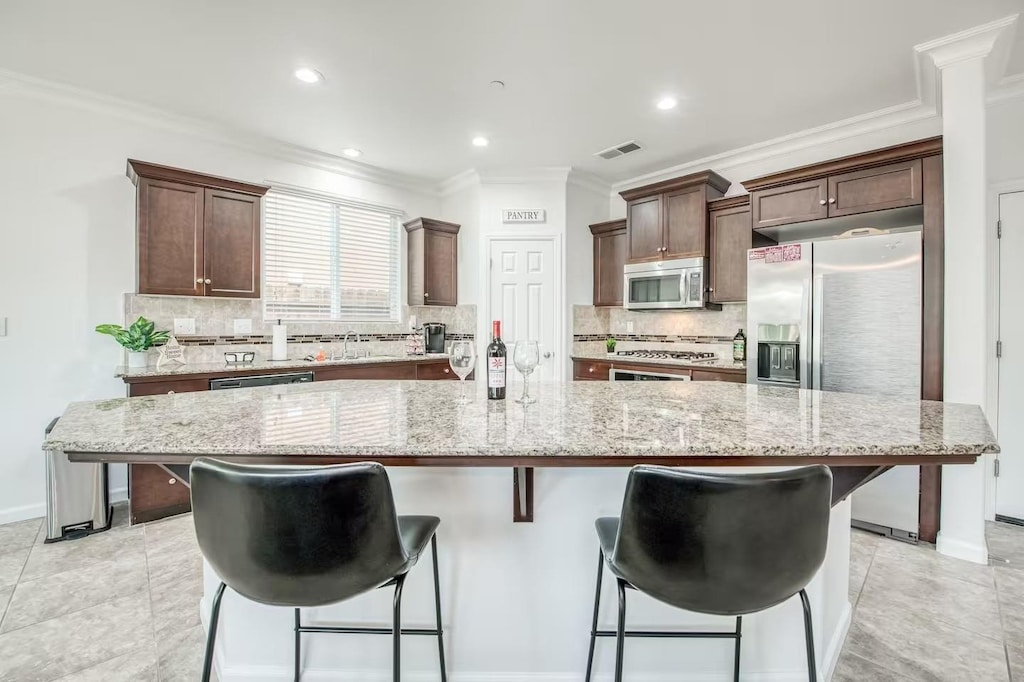 kitchen featuring light stone countertops, a large island, appliances with stainless steel finishes, and a kitchen breakfast bar