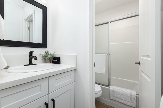 full bathroom with toilet, combined bath / shower with glass door, wood-type flooring, and vanity