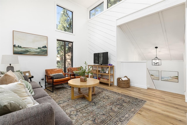 living room featuring hardwood / wood-style floors, a towering ceiling, and a chandelier