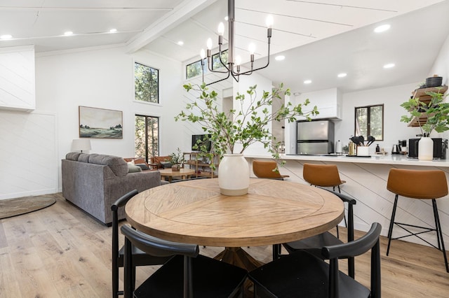 dining room with lofted ceiling with beams, an inviting chandelier, and light hardwood / wood-style flooring