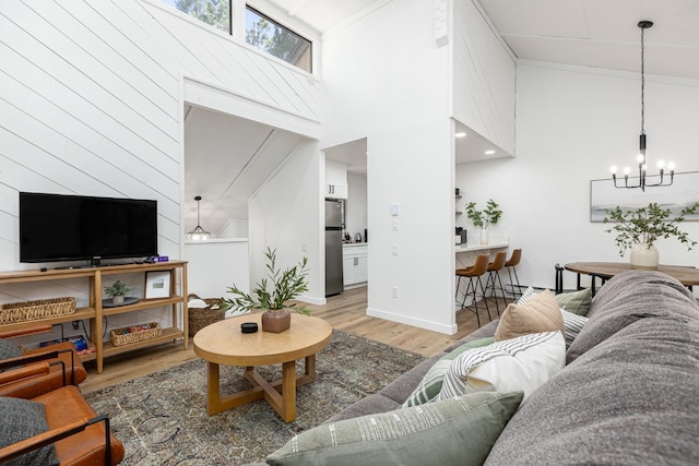 living room with a towering ceiling, wood-type flooring, and a notable chandelier