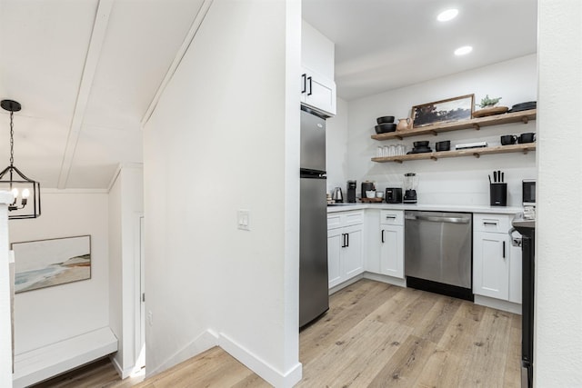 kitchen featuring appliances with stainless steel finishes, light wood-type flooring, decorative light fixtures, an inviting chandelier, and white cabinetry