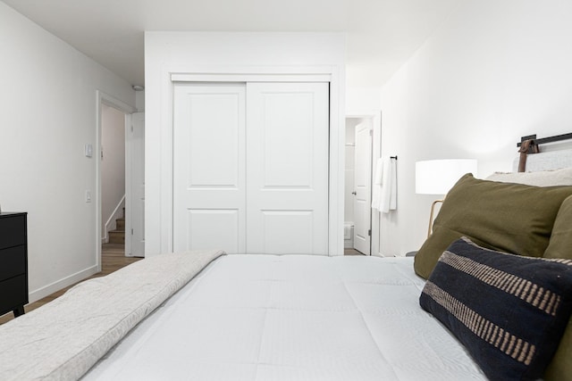 bedroom with ensuite bathroom, a closet, and dark wood-type flooring