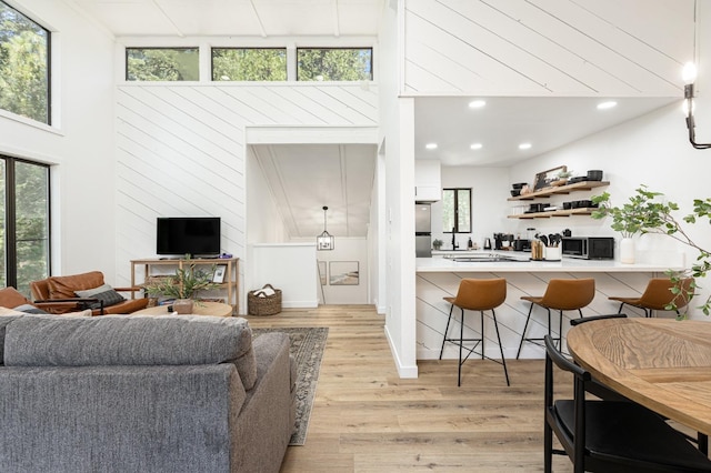 living room with a healthy amount of sunlight, a towering ceiling, and light hardwood / wood-style flooring