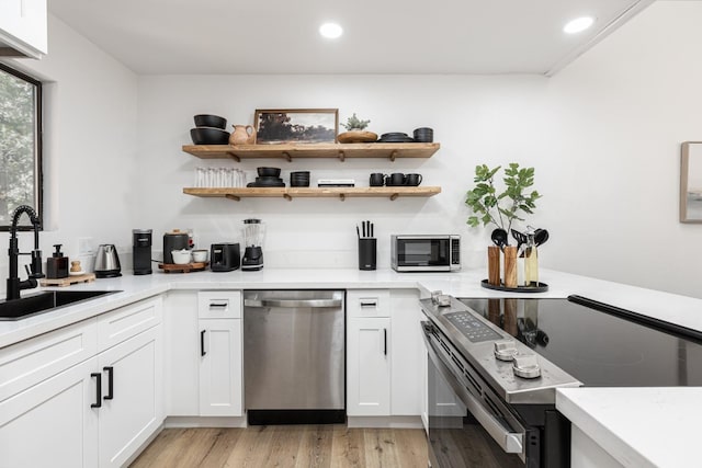 bar with white cabinetry, sink, stainless steel appliances, and light hardwood / wood-style floors