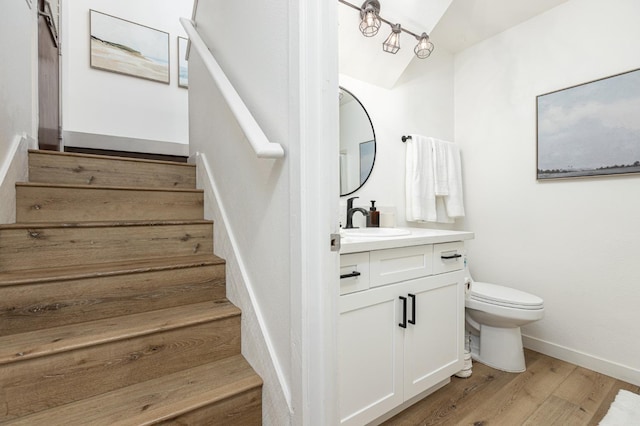 stairs with wood-type flooring, vaulted ceiling, and sink