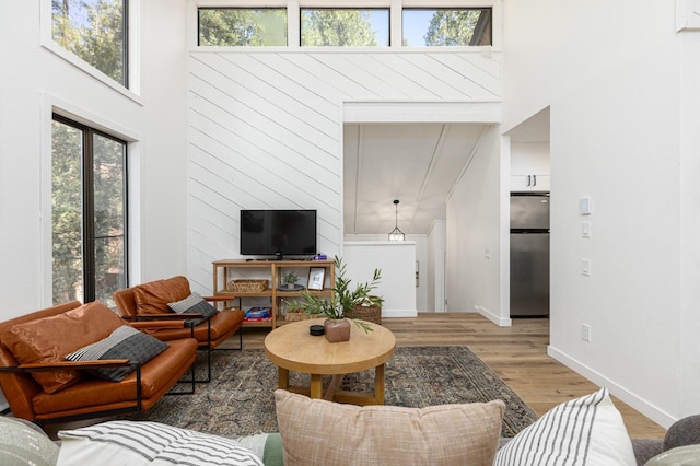 living room featuring light wood-type flooring and a towering ceiling