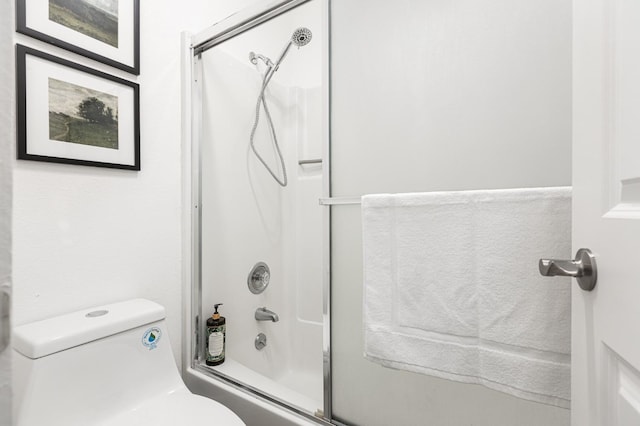 bathroom with toilet and bath / shower combo with glass door