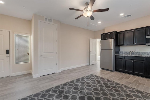 kitchen with light stone counters, light hardwood / wood-style flooring, ceiling fan, and stainless steel appliances