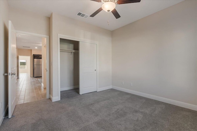 unfurnished bedroom with carpet, ceiling fan, a closet, and refrigerator