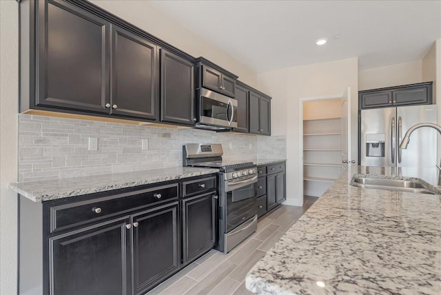 kitchen with light stone counters, sink, decorative backsplash, and stainless steel appliances