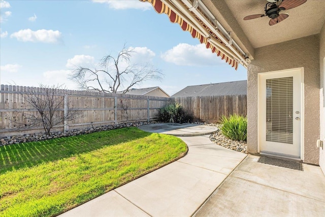 view of yard featuring ceiling fan and a patio