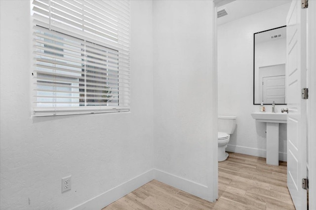 bathroom with toilet, wood-type flooring, and sink