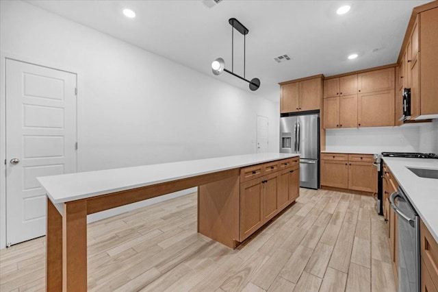 kitchen featuring stainless steel appliances, a center island, pendant lighting, and light hardwood / wood-style flooring