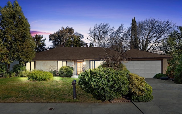 ranch-style home featuring a garage and a lawn