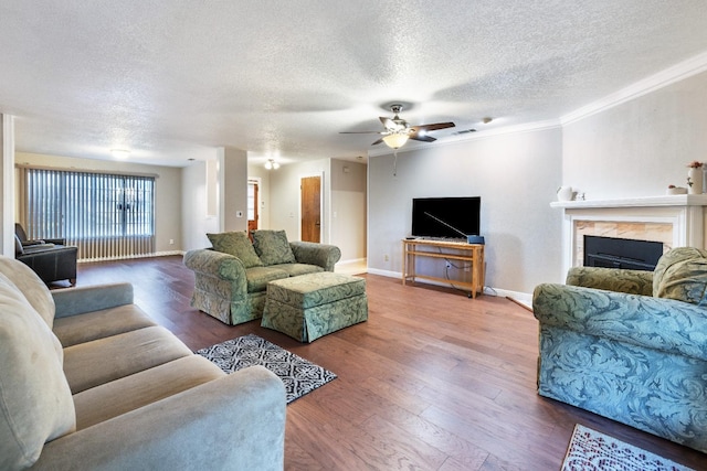 living room featuring a textured ceiling, ceiling fan, crown molding, wood-type flooring, and a fireplace